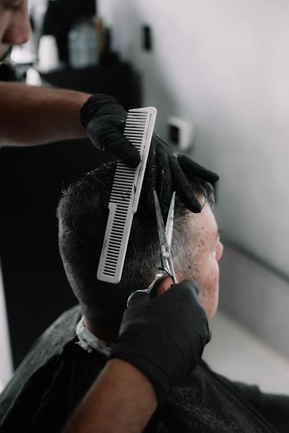 Barbero con guantes negros cortando el cabello